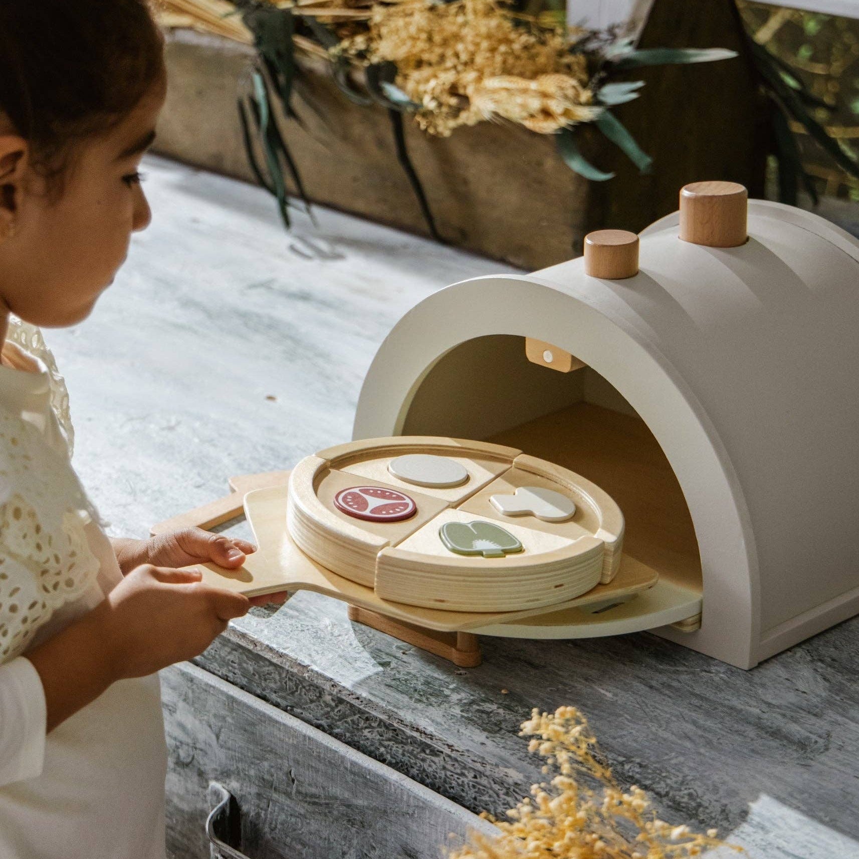 Kind speelt met een houten pizzaoven en houten pizza