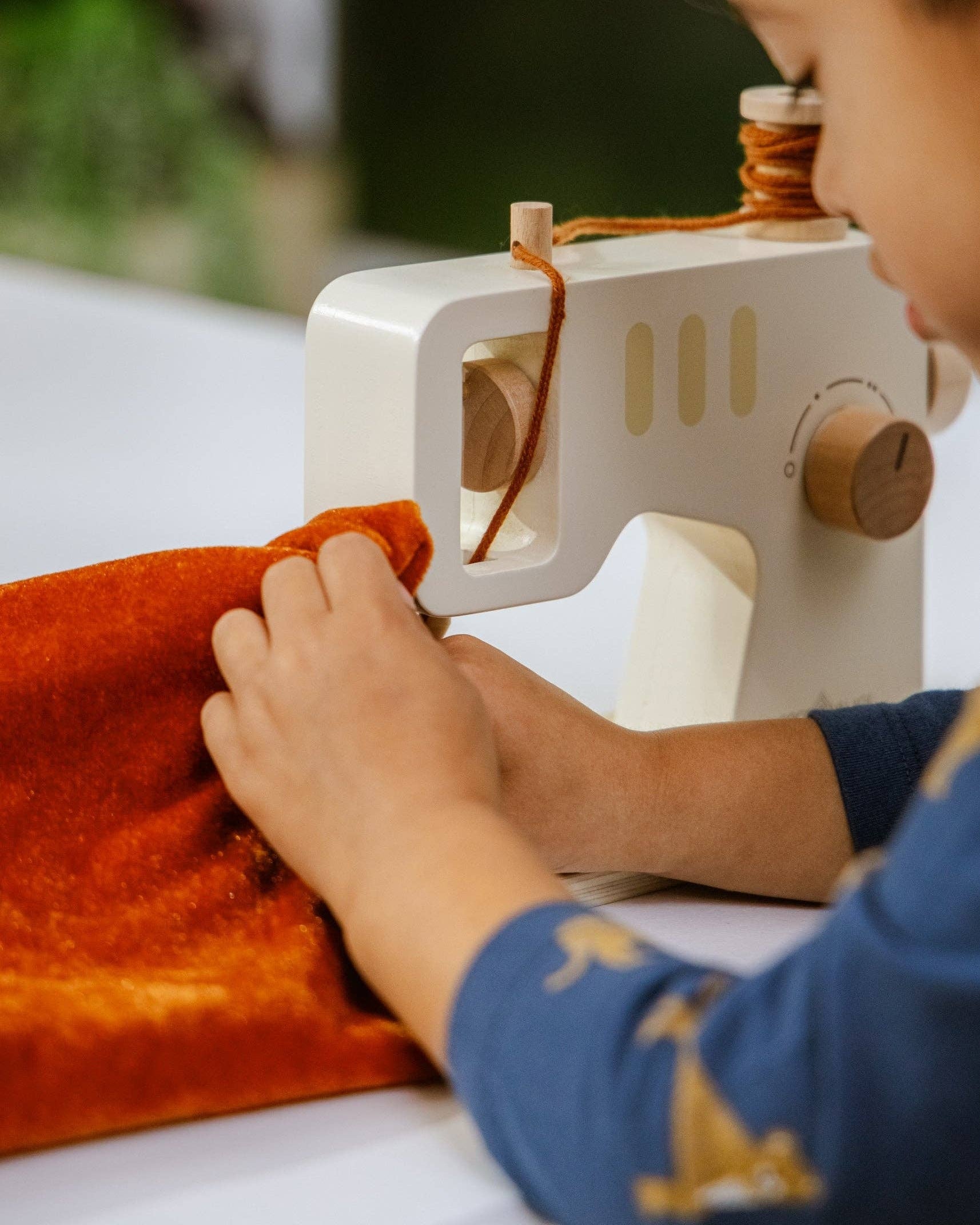 Kind speelt geconcentreerd met de houten naaimachine van Coco Village